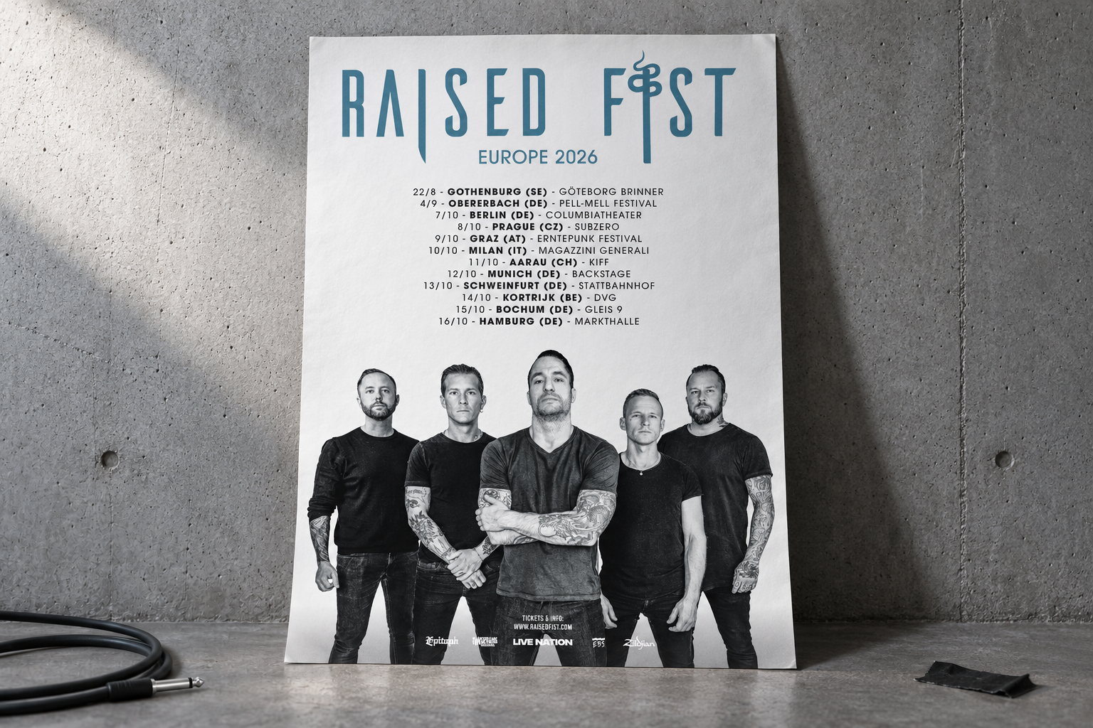 Raised Fist’s Europe 2026 tour poster leaning against a concrete wall, with a black instrument cable and gaffer tape on the floor.